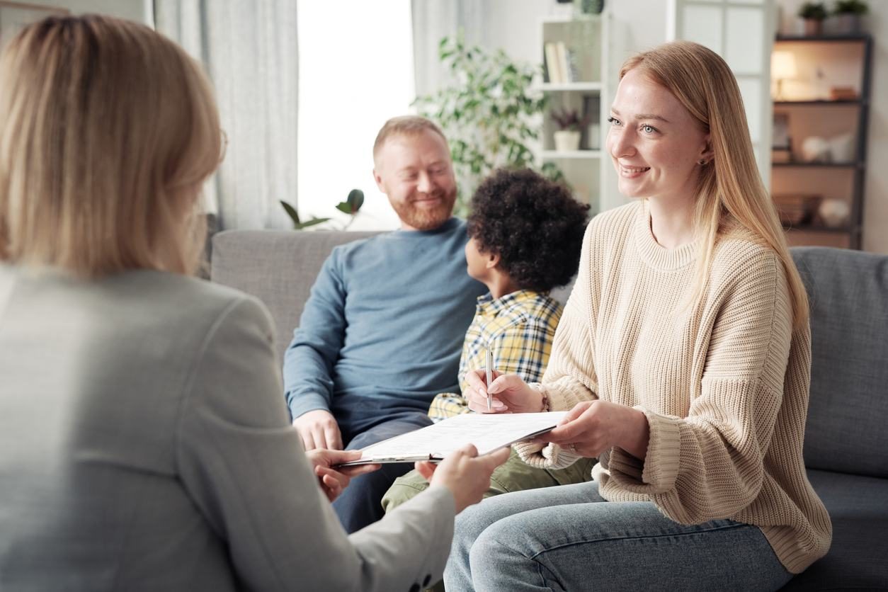 A babysitter chatting with a family in their living room